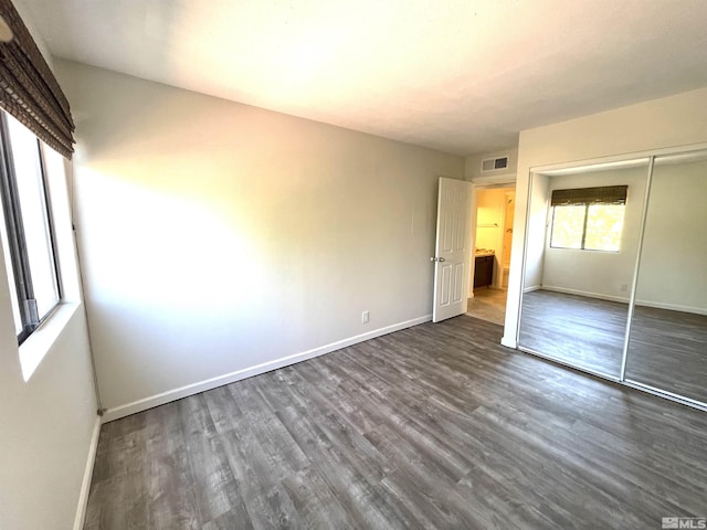 unfurnished bedroom with a closet and dark hardwood / wood-style flooring