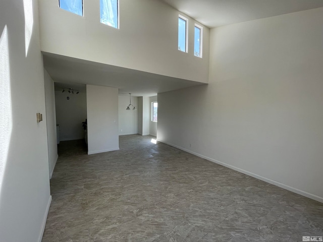 unfurnished room featuring a towering ceiling and a healthy amount of sunlight