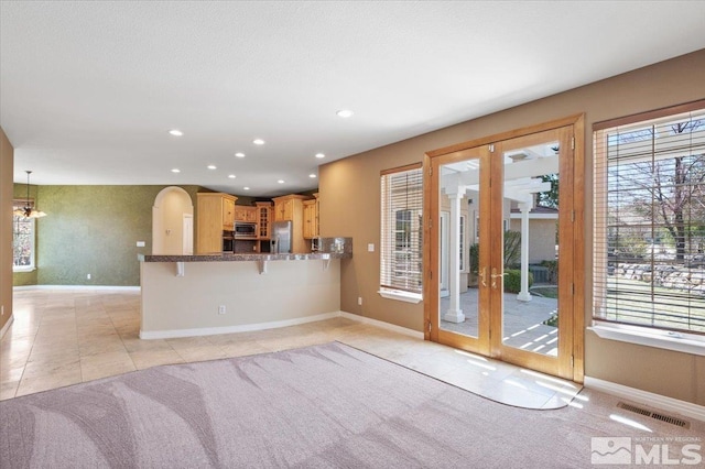 kitchen with french doors, stainless steel appliances, light tile floors, and decorative light fixtures