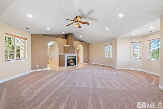 unfurnished living room featuring a wealth of natural light, light carpet, and a fireplace