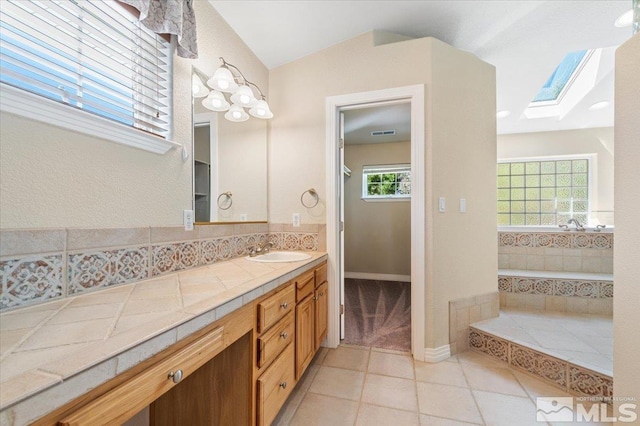 bathroom featuring tile flooring, plenty of natural light, vaulted ceiling with skylight, and large vanity