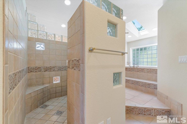 bathroom featuring a skylight and a tile shower