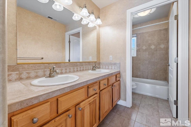 full bathroom featuring vanity with extensive cabinet space, toilet, tiled shower / bath combo, double sink, and tile floors