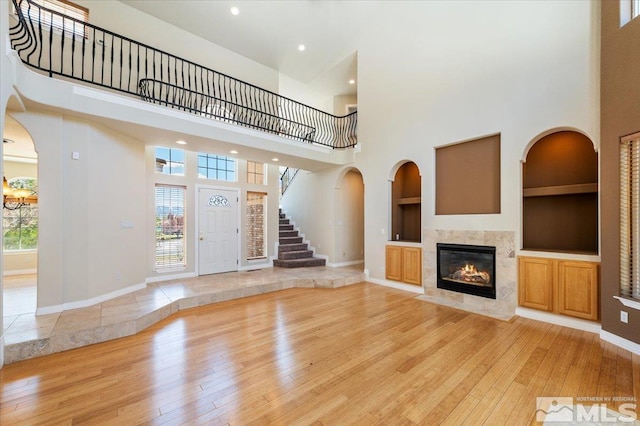 unfurnished living room with built in features, light wood-type flooring, a wealth of natural light, and a fireplace