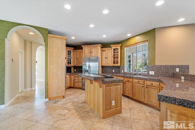 kitchen with a kitchen island, tasteful backsplash, a kitchen breakfast bar, sink, and light tile floors