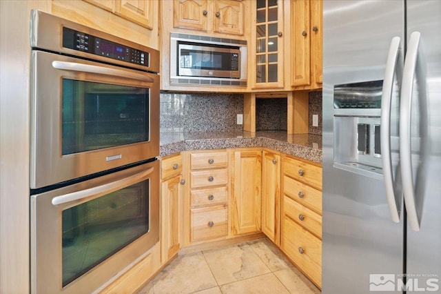 kitchen featuring appliances with stainless steel finishes, light brown cabinetry, backsplash, and light tile floors