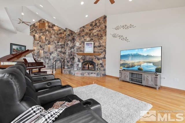 living room featuring a stone fireplace, high vaulted ceiling, ceiling fan, and hardwood / wood-style floors