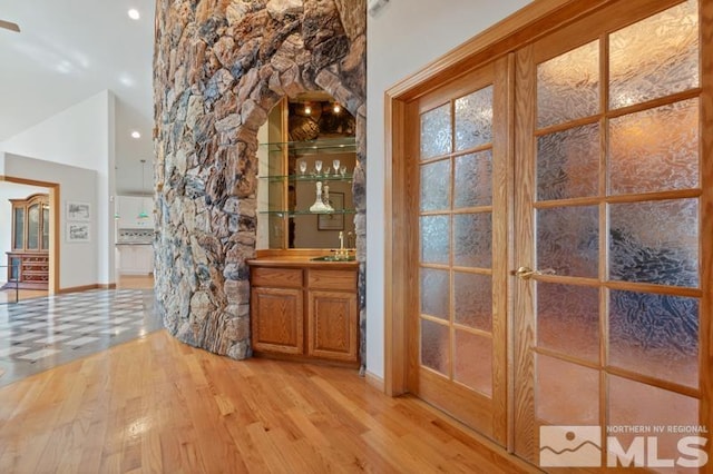 bar with light hardwood / wood-style flooring and sink