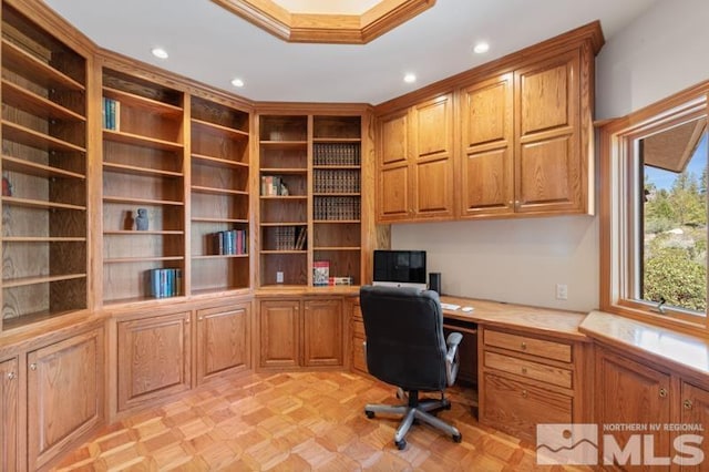 unfurnished office featuring built in desk, light parquet flooring, and ornamental molding