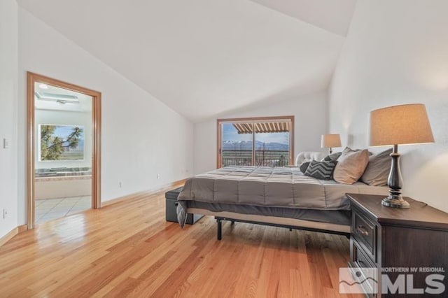 bedroom featuring light hardwood / wood-style flooring, connected bathroom, and vaulted ceiling