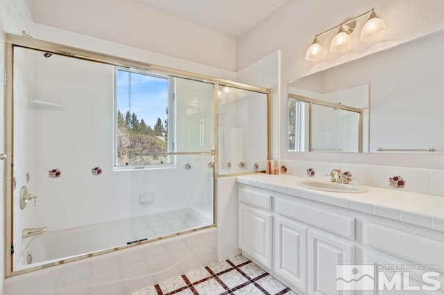 bathroom featuring large vanity and bath / shower combo with glass door