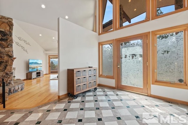 entryway with a fireplace, high vaulted ceiling, ceiling fan, and light tile floors