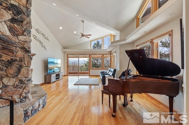 misc room featuring high vaulted ceiling, light hardwood / wood-style floors, ceiling fan, and a fireplace