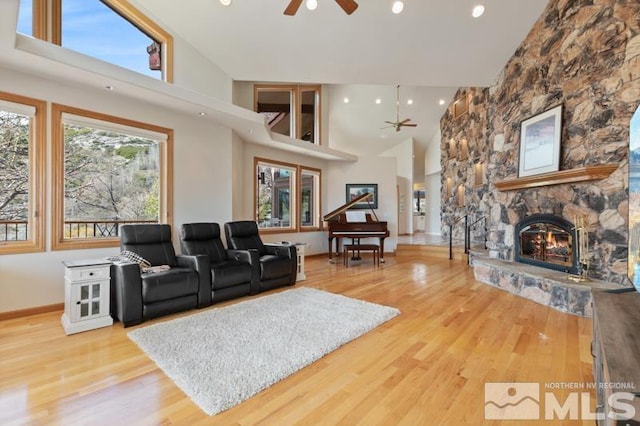 living room with high vaulted ceiling, hardwood / wood-style floors, ceiling fan, and a fireplace