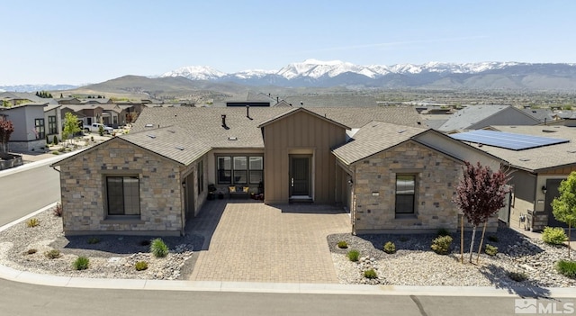 view of front of home with a mountain view and solar panels