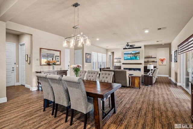 dining room featuring dark hardwood / wood-style flooring and ceiling fan with notable chandelier