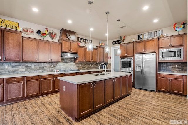 kitchen with hanging light fixtures, stainless steel appliances, hardwood / wood-style flooring, sink, and tasteful backsplash