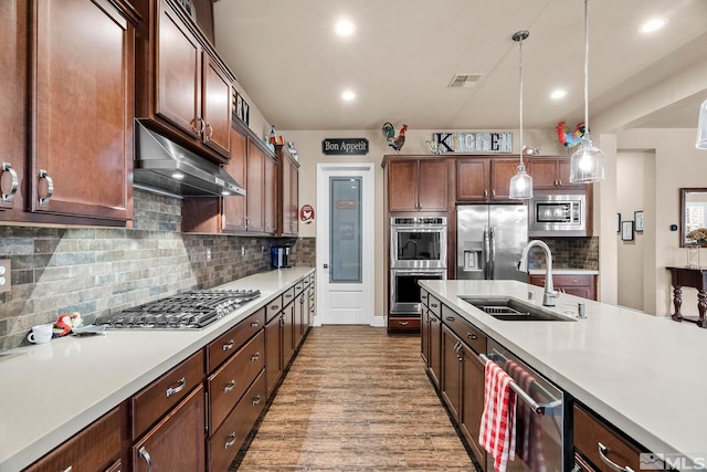 kitchen with stainless steel appliances, backsplash, hardwood / wood-style floors, sink, and pendant lighting