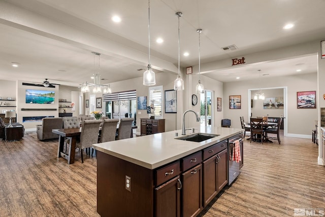 kitchen with an island with sink, light wood-type flooring, and pendant lighting