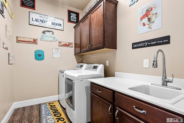 washroom featuring independent washer and dryer, sink, cabinets, and wood-type flooring