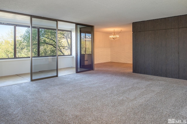 empty room featuring an inviting chandelier, carpet, and a textured ceiling