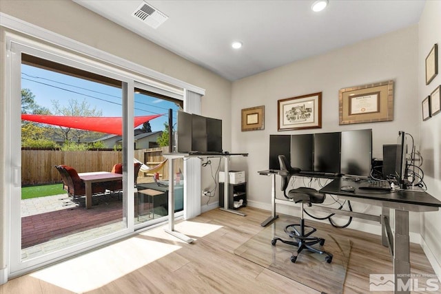 office with light hardwood / wood-style flooring and a wealth of natural light