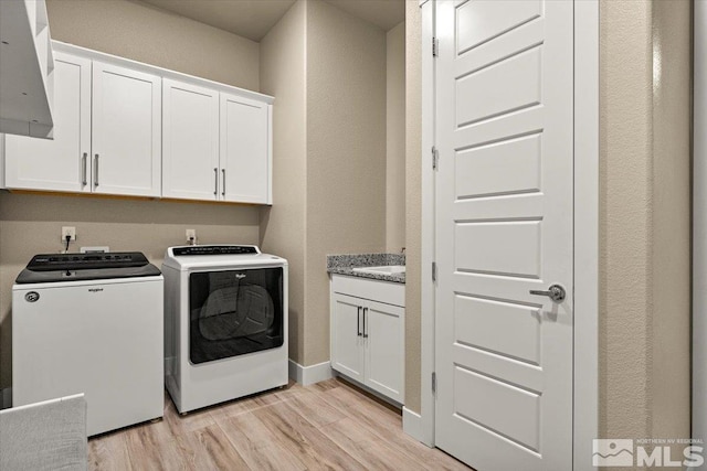 laundry room with cabinets, light wood-type flooring, sink, and separate washer and dryer