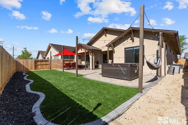 back of house with a hot tub, a yard, and a patio