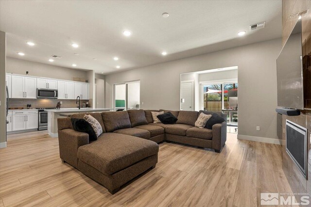 living room featuring a fireplace, sink, and light hardwood / wood-style floors