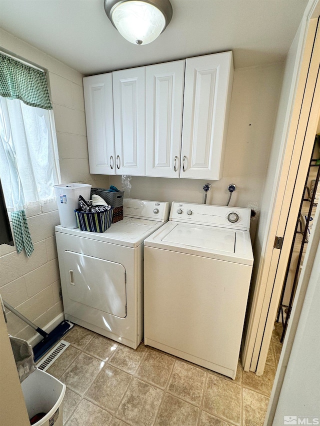 washroom featuring cabinets, light tile floors, and washing machine and clothes dryer