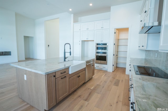 kitchen featuring white cabinetry, light stone countertops, sink, a spacious island, and appliances with stainless steel finishes