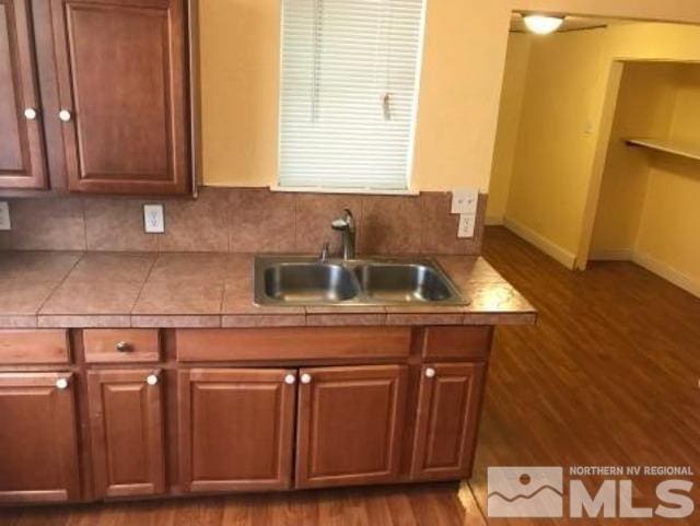 kitchen featuring dark hardwood / wood-style flooring, backsplash, sink, and tile countertops