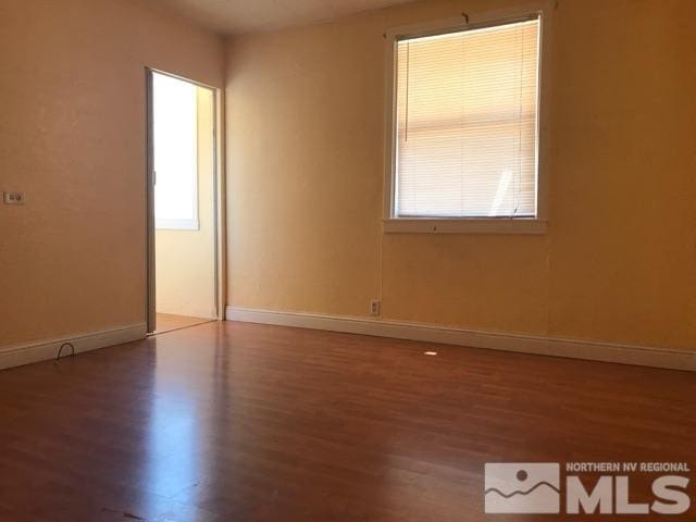 empty room with a wealth of natural light and hardwood / wood-style floors