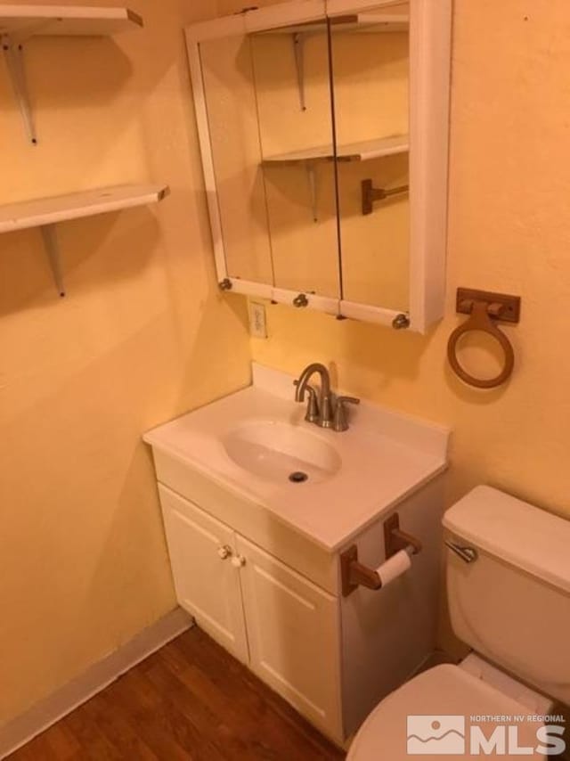 bathroom featuring wood-type flooring, vanity, and toilet