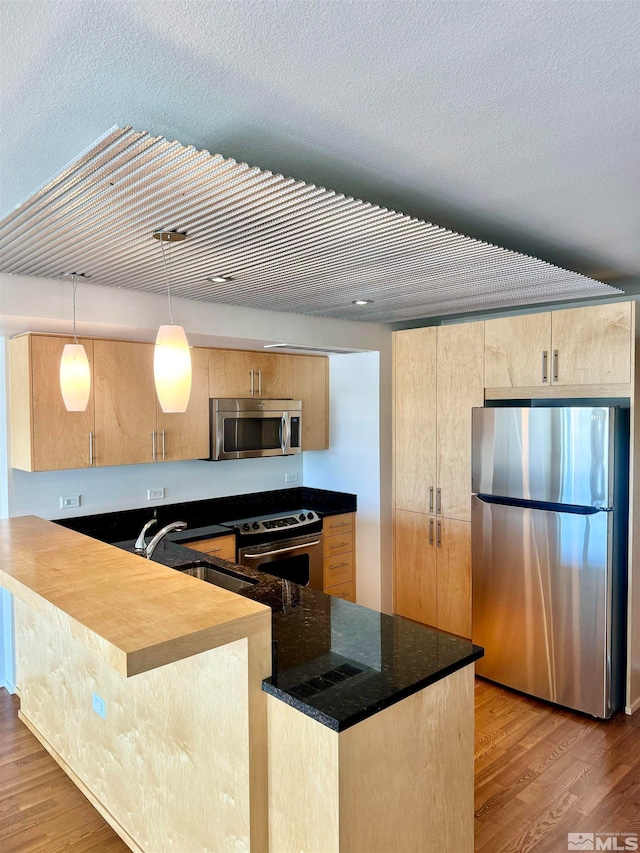 kitchen featuring light hardwood / wood-style floors, appliances with stainless steel finishes, kitchen peninsula, and sink