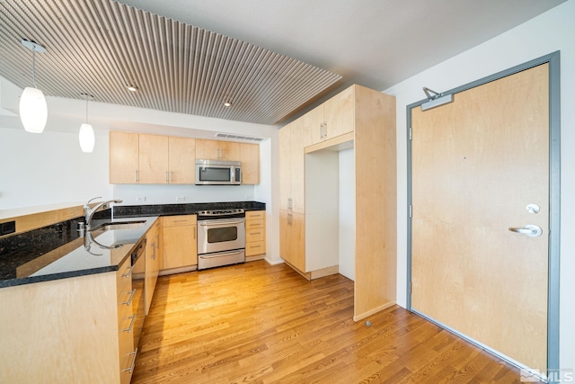 kitchen with light brown cabinetry, appliances with stainless steel finishes, and light wood-type flooring