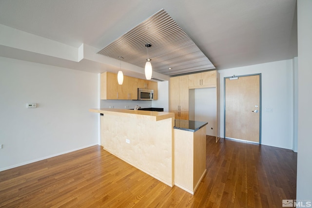 kitchen with hardwood / wood-style floors, hanging light fixtures, light brown cabinets, and kitchen peninsula