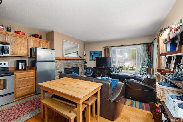 kitchen with light hardwood / wood-style floors, stainless steel appliances, and a fireplace