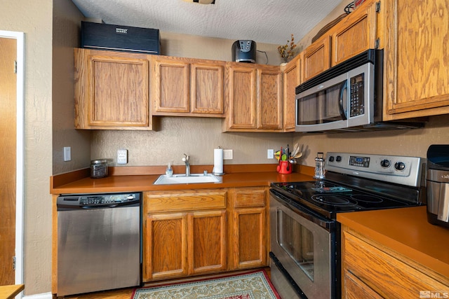 kitchen with appliances with stainless steel finishes, a textured ceiling, and sink