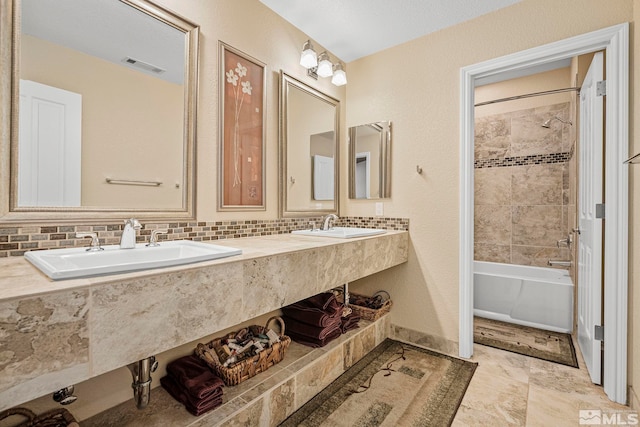 bathroom featuring dual sinks, tiled shower / bath combo, tile floors, and vanity with extensive cabinet space