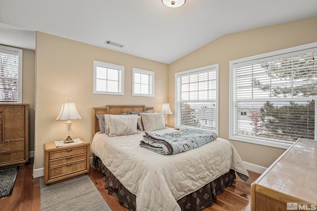 bedroom featuring hardwood / wood-style flooring, vaulted ceiling, and multiple windows