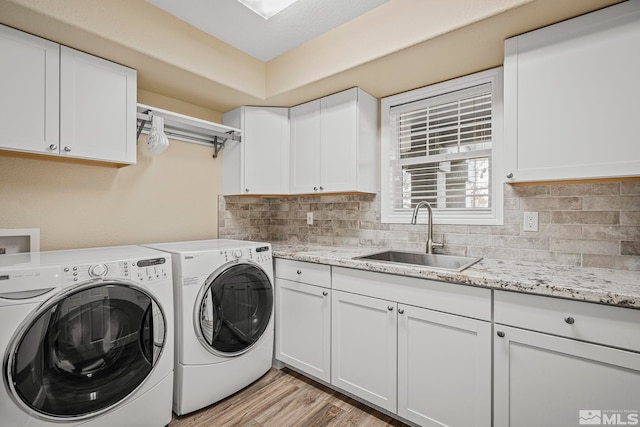 washroom with hookup for a washing machine, light hardwood / wood-style flooring, cabinets, independent washer and dryer, and sink