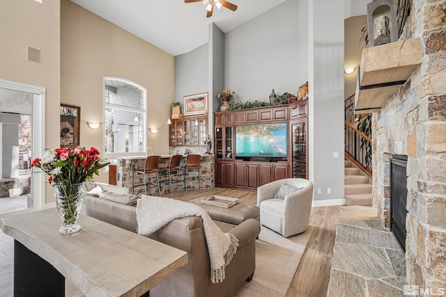 living room featuring high vaulted ceiling, wood-type flooring, ceiling fan, and a fireplace