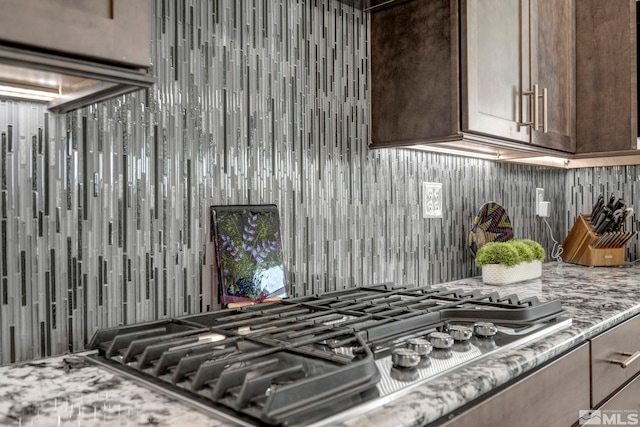 kitchen with dark brown cabinetry, light stone countertops, and stainless steel gas cooktop