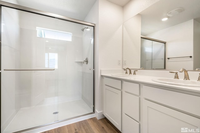 bathroom with hardwood / wood-style flooring, double sink, a shower with shower door, and oversized vanity