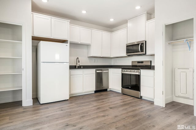 kitchen featuring sink, stainless steel appliances, light wood-type flooring, and white cabinetry