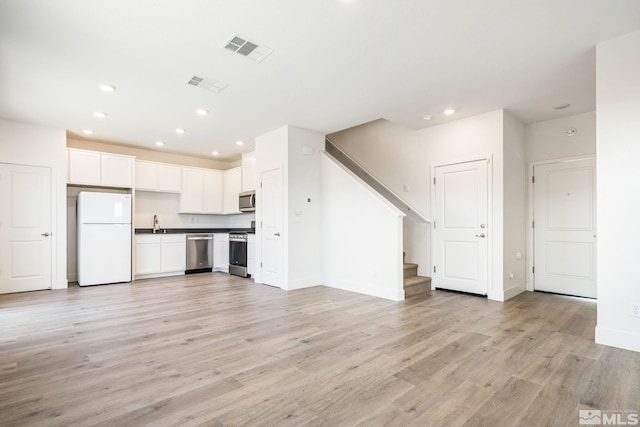 unfurnished living room featuring sink and light wood-type flooring