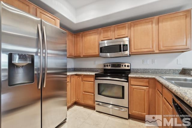 kitchen featuring appliances with stainless steel finishes, sink, stone countertops, and light tile floors