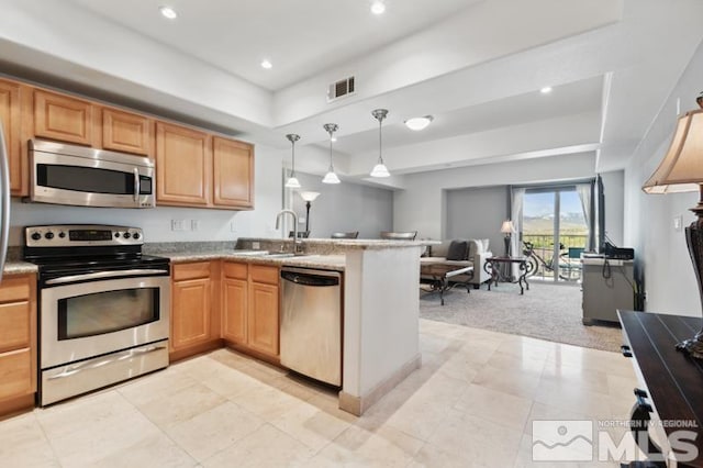 kitchen featuring kitchen peninsula, pendant lighting, light carpet, sink, and appliances with stainless steel finishes