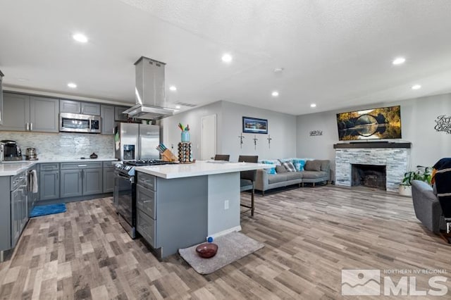 kitchen featuring light hardwood / wood-style floors, a center island, stainless steel appliances, and a fireplace